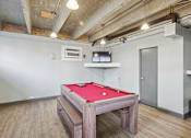 Thumbnail 1 of 13 - A pool table in a room with a concrete ceiling and wooden flooring.