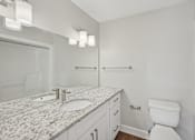 Thumbnail 21 of 27 - A white bathroom with a marble counter top and a toilet.