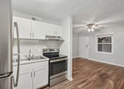 Thumbnail 5 of 11 - A kitchen with white cabinets and stainless steel appliances.