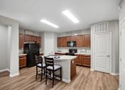 Thumbnail 4 of 32 - A kitchen with a black refrigerator and wooden cabinets.