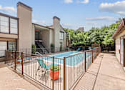 Thumbnail 10 of 14 - A pool surrounded by a fence with a chair and a potted plant.