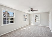 Thumbnail 7 of 15 - A room with a ceiling fan and three windows.
