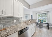Thumbnail 2 of 31 - A kitchen with a granite countertop and a dining table with chairs.