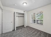 Thumbnail 21 of 25 - A room with a carpeted floor and a window with blinds.