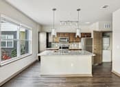 Thumbnail 34 of 39 - A kitchen with a white island and wooden cabinets.