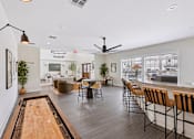 Thumbnail 21 of 26 - A clubroom with a shaggy rug and a long table with chairs with shuffleboard..