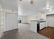 Thumbnail 18 of 25 - A spacious kitchen and living room with white cabinetry and a grey carpet.