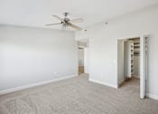 Thumbnail 14 of 27 - A room with a ceiling fan and a carpeted floor.