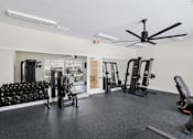 Thumbnail 23 of 26 - A spacious gym with a variety of equipment including dumbbells, weight machines, and a bench press.
