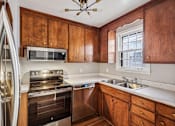 Thumbnail 2 of 15 - A kitchen with wooden cabinets and stainless steel appliances.