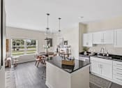 Thumbnail 8 of 26 - A kitchen with a black countertop and white cabinets and dining room..