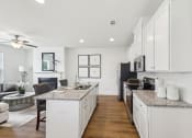 Thumbnail 4 of 25 - an open kitchen and living room with white cabinets and granite counter tops