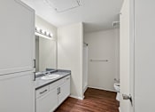 Thumbnail 3 of 25 - A bathroom with a sink, mirror, and toilet.