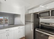 Thumbnail 2 of 27 - A kitchen with a stainless steel refrigerator and oven.