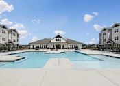 Thumbnail 1 of 26 - A large swimming pool in front of a building with a white roof.
