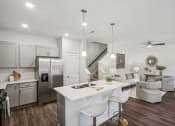 Thumbnail 12 of 25 - a kitchen and living room with a white counter top and a stainless steel refrigerator