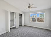 Thumbnail 15 of 27 - A room with a ceiling fan and a window overlooking a cityscape.