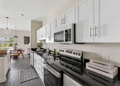 Thumbnail 6 of 26 - A modern kitchen with black countertops and white cabinets.