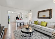 Thumbnail 6 of 19 - A living room with a white couch and a coffee table.