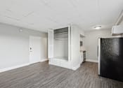 Thumbnail 6 of 13 - A black refrigerator sits in a kitchen with white cabinets and a white wall.
