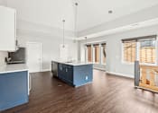 Thumbnail 5 of 13 - A kitchen with a blue island and wooden floors.