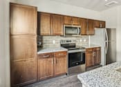 Thumbnail 28 of 39 - A kitchen with wooden cabinets and stainless steel appliances.