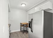 Thumbnail 4 of 13 - A kitchen area with a refrigerator, a table and chairs.