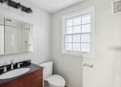 Thumbnail 15 of 15 - A bathroom with a toilet, sink, and window.