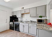 Thumbnail 1 of 19 - A kitchen with a black oven and white cabinets.