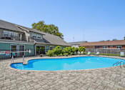 Thumbnail 27 of 35 - A swimming pool surrounded by a brick patio and apartment buildings.