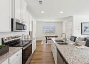 Thumbnail 5 of 25 - an open kitchen and living room with granite counter tops