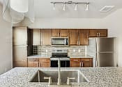Thumbnail 21 of 39 - A kitchen with a granite countertop and stainless steel appliances.