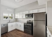 Thumbnail 1 of 27 - A kitchen with white cabinets and stainless steel appliances.