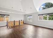 Thumbnail 7 of 13 - A room with wooden floors and a large arched window.