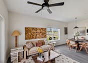 Thumbnail 11 of 26 - A living room with a couch, coffee table, and a ceiling fan.
