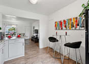 Thumbnail 3 of 19 - A kitchen with a bar stool and a fridge.