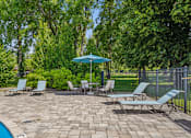 Thumbnail 25 of 35 - A poolside area with a blue umbrella and several lounge chairs.