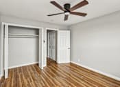 Thumbnail 14 of 15 - A room with a ceiling fan and wooden floors.