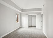 Thumbnail 11 of 13 - A large, empty room with a carpeted floor and white walls.