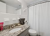 Thumbnail 12 of 19 - A bathroom with a sink, toilet, and shower curtain.