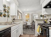 Thumbnail 3 of 14 - A kitchen with white cabinets and a black stove top oven.