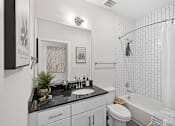 Thumbnail 14 of 26 - A bathroom with a black granite countertop and white tiles.