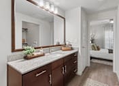Thumbnail 7 of 47 - A bathroom with a vanity, mirror, and a bedroom in the background.