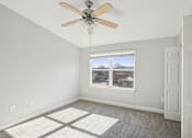 Thumbnail 18 of 27 - A room with a ceiling fan and a window overlooking a cityscape.