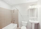 Thumbnail 8 of 13 - A white bathroom with a tub, toilet, and sink.