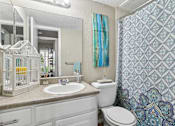 Thumbnail 6 of 14 - A bathroom with a white toilet, sink, and a birdcage on the counter.