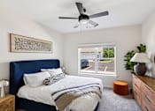 Thumbnail 16 of 26 - A bedroom with a bed, a ceiling fan, and a window overlooking a parking lot.