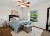 Thumbnail 10 of 19 - A bedroom with a bed, a ceiling fan, and a window.