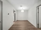 Thumbnail 6 of 35 - A long, empty hallway with wood flooring and white walls.