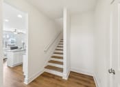 Thumbnail 12 of 25 - a living room with white walls and a staircase with wood floors